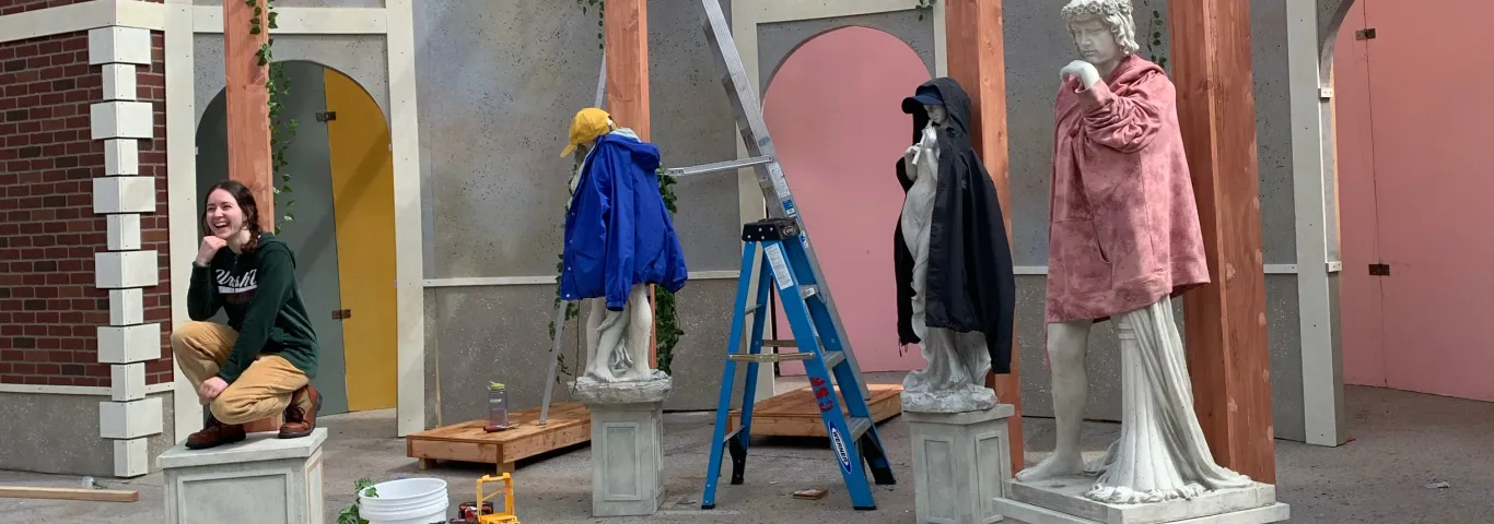 Katie Plum poses with statues on Shakespeare set