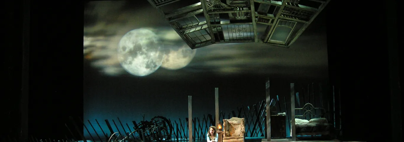 Young woman sitting alone on a stage, set design by Rob Morgan